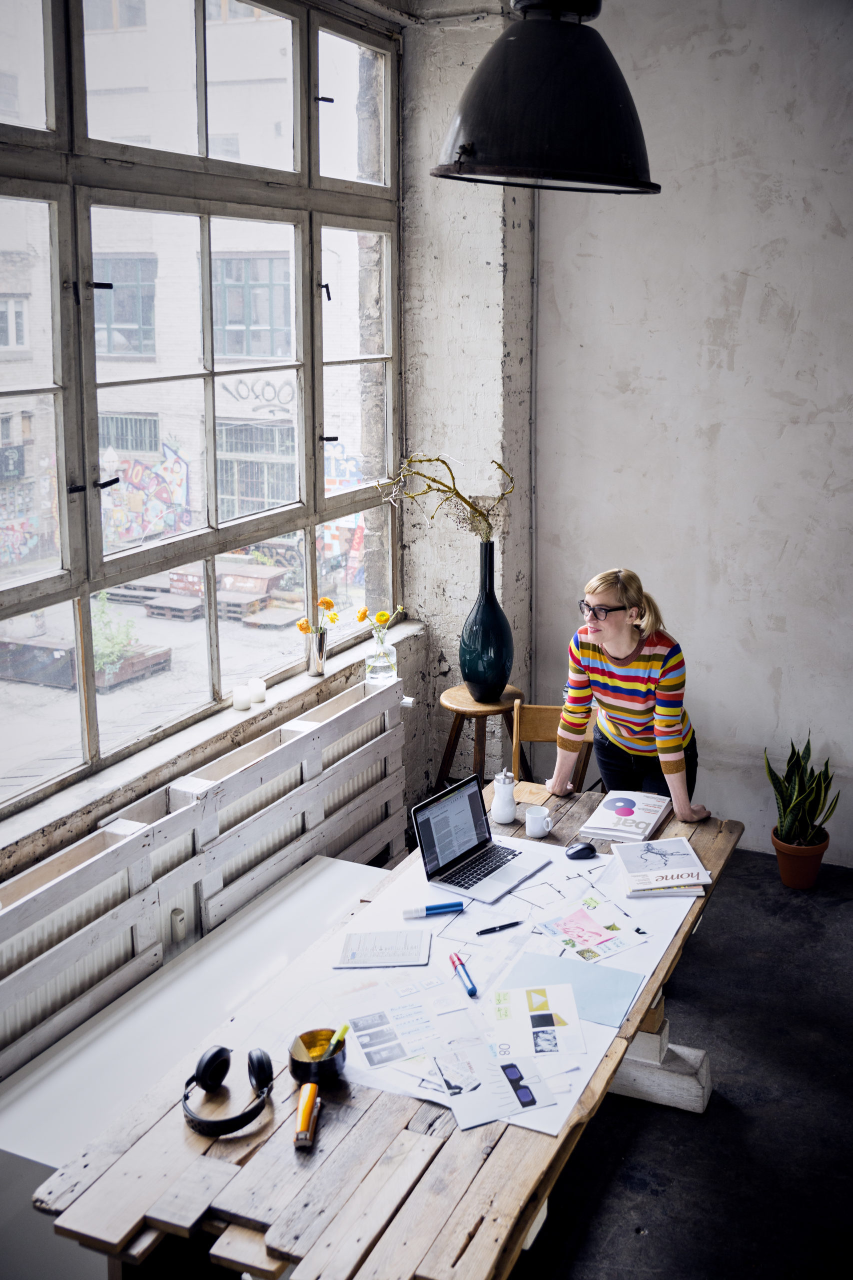 Woman standing at desk in a loft looking through window